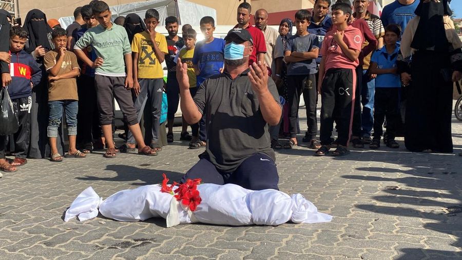Ibrahim, ayah dari anak laki-laki Palestina Elias Abu Shamaleh, yang terluka dalam serangan udara Israel dan kemudian meninggal karena kekurangan obat-obatan, menurut pamannya, berdoa di samping jenazahnya selama pemakamannya di Khan Younis di Jalur Gaza selatan pada bulan Oktober. 26 Agustus 2023. (REUTERS/Arafat Barbakh)