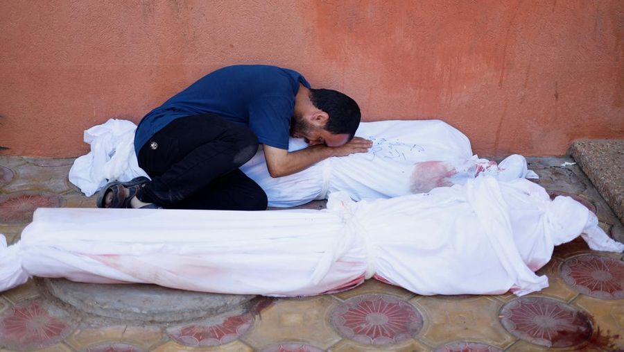 Pria Palestina Mohammed al-Akhras berduka atas jenazah putrinya Jana ketika jenazah istrinya terbaring di tanah setelah mereka terbunuh oleh serangan Israel, saat konflik antara Israel dan kelompok Islam Palestina Hamas berlanjut, di Khan Younis di selatan Jalur Gaza, 26 Oktober 2023. (REUTERS/Mohammed Salem)