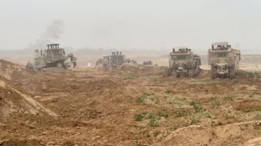 Kendaraan lapis baja Pasukan Pertahanan Israel (IDF) menunggu saat buldoser lapis baja membersihkan jalan yang dipenuhi puing-puing di lokasi yang disebut sebagai Gaza, saat konflik antara Israel dan kelompok Islam Palestina Hamas terus berlanjut, dalam tangkapan layar yang diperoleh dari video selebaran yang dirilis di 29 Oktober 2023. (Israeli Defence Forces/Handout via REUTERS)