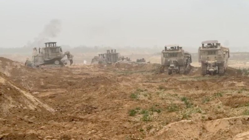 Kendaraan lapis baja Pasukan Pertahanan Israel (IDF) menunggu saat buldoser lapis baja membersihkan jalan yang dipenuhi puing-puing di lokasi yang disebut sebagai Gaza, saat konflik antara Israel dan kelompok Islam Palestina Hamas terus berlanjut, dalam tangkapan layar yang diperoleh dari video selebaran yang dirilis di 29 Oktober 2023. (Israeli Defence Forces/Handout via REUTERS)