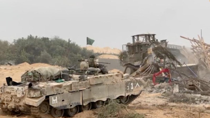 Kendaraan lapis baja Pasukan Pertahanan Israel (IDF) menunggu saat buldoser lapis baja membersihkan jalan yang dipenuhi puing-puing di lokasi yang disebut sebagai Gaza, saat konflik antara Israel dan kelompok Islam Palestina Hamas terus berlanjut, dalam tangkapan layar yang diperoleh dari video selebaran yang dirilis di 29 Oktober 2023. (Israeli Defence Forces/Handout via REUTERS)