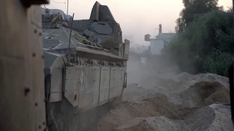Kendaraan lapis baja Pasukan Pertahanan Israel (IDF) menunggu saat buldoser lapis baja membersihkan jalan yang dipenuhi puing-puing di lokasi yang disebut sebagai Gaza, saat konflik antara Israel dan kelompok Islam Palestina Hamas terus berlanjut, dalam tangkapan layar yang diperoleh dari video selebaran yang dirilis di 29 Oktober 2023. (Israeli Defence Forces/Handout via REUTERS)