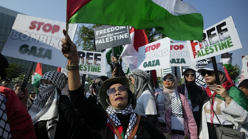 Seorang pengunjuk rasa pro-Palestina memegang kain putih dibuat menyerupai anak yang meninggal saat demonstrasi di Ottawa, Ontario, Minggu, 22 Oktober 2023. (Spencer Colby/The Canadian Press via AP)