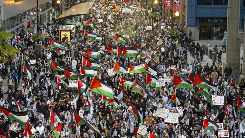 Seorang pengunjuk rasa pro-Palestina memegang kain putih dibuat menyerupai anak yang meninggal saat demonstrasi di Ottawa, Ontario, Minggu, 22 Oktober 2023. (Spencer Colby/The Canadian Press via AP)