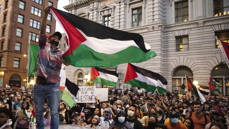 Seorang pengunjuk rasa pro-Palestina memegang kain putih dibuat menyerupai anak yang meninggal saat demonstrasi di Ottawa, Ontario, Minggu, 22 Oktober 2023. (Spencer Colby/The Canadian Press via AP)