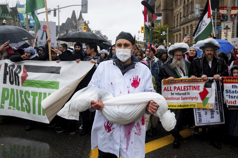 Seorang pengunjuk rasa pro-Palestina memegang kain putih dibuat menyerupai anak yang meninggal saat demonstrasi di Ottawa, Ontario, Minggu, 22 Oktober 2023. (Spencer Colby/The Canadian Press via AP) Seorang pengunjuk rasa pro-Palestina memegang kain putih dibuat menyerupai anak yang meninggal saat demonstrasi di Ottawa, Ontario, Minggu, 22 Oktober 2023. (Spencer Colby/The Canadian Press via AP)