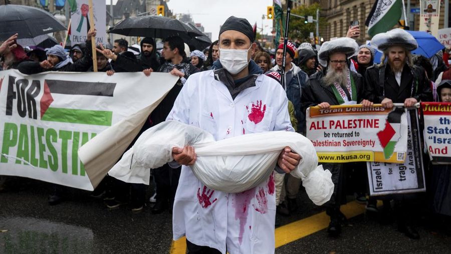 Seorang pengunjuk rasa pro-Palestina memegang kain putih dibuat menyerupai anak yang meninggal saat demonstrasi di Ottawa, Ontario, Minggu, 22 Oktober 2023. (Spencer Colby/The Canadian Press via AP)