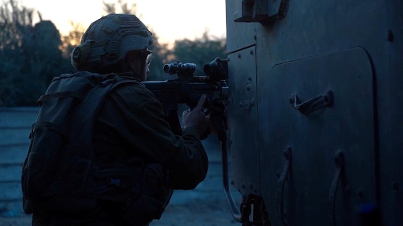 Kendaraan lapis baja Pasukan Pertahanan Israel (IDF) menunggu saat buldoser lapis baja membersihkan jalan yang dipenuhi puing-puing di lokasi yang disebut sebagai Gaza, saat konflik antara Israel dan kelompok Islam Palestina Hamas terus berlanjut, dalam tangkapan layar yang diperoleh dari video selebaran yang dirilis di 29 Oktober 2023. (Israeli Defence Forces/Handout via REUTERS)