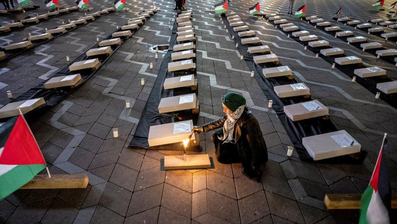 Seorang pengunjuk rasa pro-Palestina memegang kain putih dibuat menyerupai anak yang meninggal saat demonstrasi di Ottawa, Ontario, Minggu, 22 Oktober 2023. (Spencer Colby/The Canadian Press via AP)