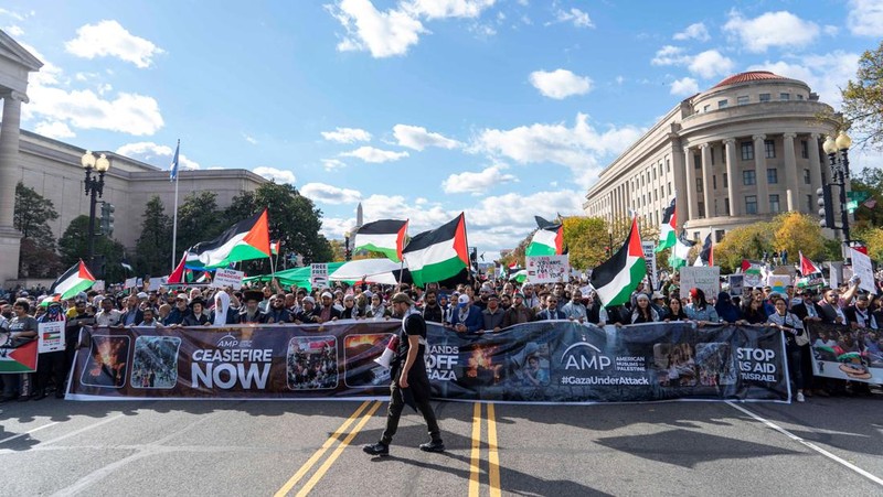 Seorang pengunjuk rasa pro-Palestina memegang kain putih dibuat menyerupai anak yang meninggal saat demonstrasi di Ottawa, Ontario, Minggu, 22 Oktober 2023. (Spencer Colby/The Canadian Press via AP)