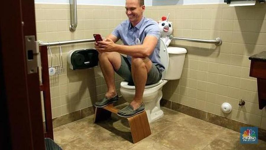 Seorang pria duduk di toilet sambil bermain telepon genggam. (Dok. վ Make It)