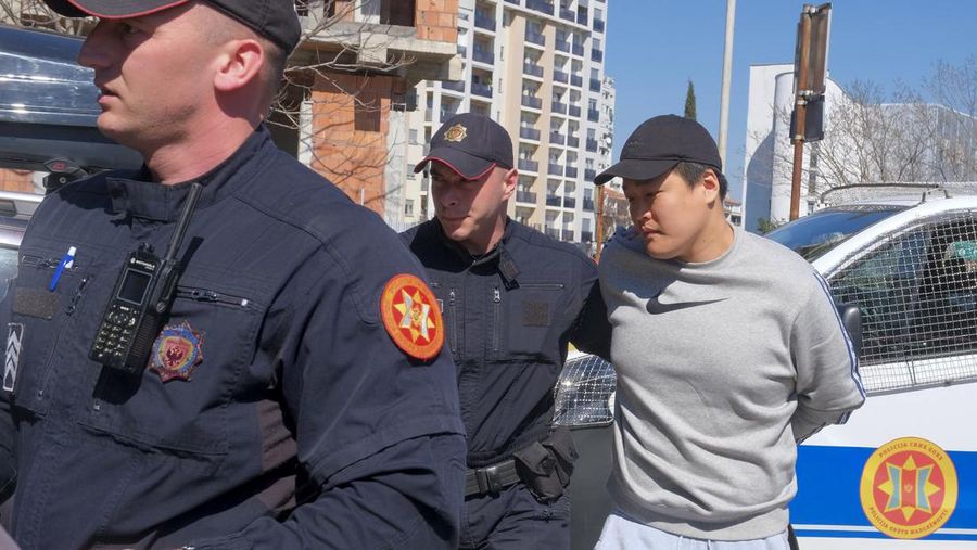 Petugas polisi Montenegro mengawal seseorang yang diyakini sebagai salah satu buronan paling dicari, warga negara Korea Selatan, pendiri Terraform Labs Do Kwon di ibu kota Montenegro, Podgorica, Jumat, 24 Maret 2023. (AP Photo/Risto Bozovic)
