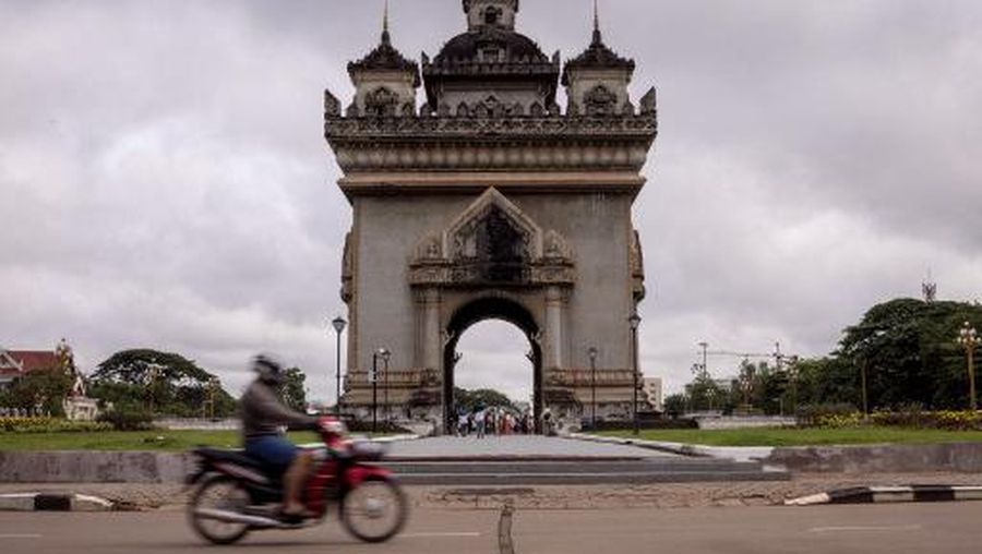 LAOS-LIFESTYLE In this picture taken on October 28, 2023 a man rides his motorbike past the Patuxai monument in Vientiane. (Photo by Jack TAYLOR / AFP)