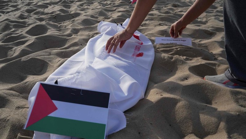 Seratus dua puluh kain kafan yang dipasang oleh anggota LSM Rio da Paz, di pantai untuk menghormati anak-anak Palestina yang terbunuh dalam konflik Israel-Hamas Gaza yang sedang berlangsung, selama demonstrasi pro-Palestina di Rio de Janeiro, Brasil, 3 November 2023. (REUTERS/Ian Cheibub)