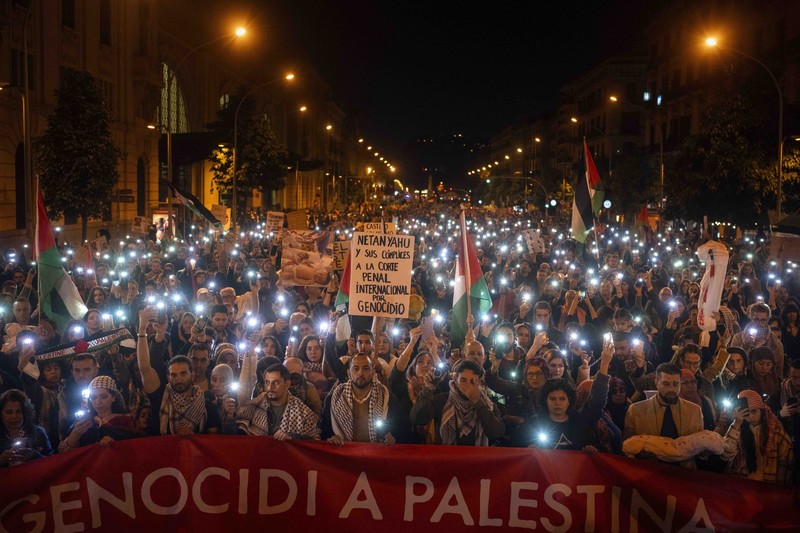 Demonstrators use the flashlights on their mobile phones as they protest against Israeli attacks on Gaza, in Barcelona, Spain, Saturday, Nov. 11, 2023. (AP Photo/Emilio Morenatti)
