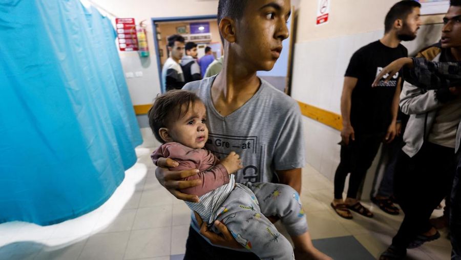 Seorang pria membawa seorang anak Palestina di rumah sakit setelah serangan Israel, di tengah konflik yang sedang berlangsung antara Israel dan kelompok Palestina Hamas, di Khan Younis di selatan Jalur Gaza, Senin (13/11/2023). (REUTERS/Mohammed Salem)