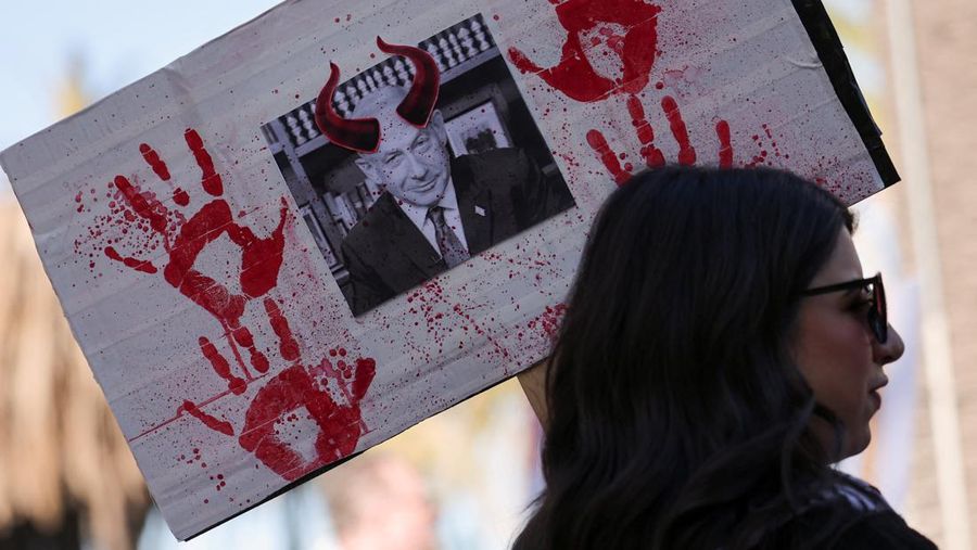 Seorang pengunjuk rasa mengacungkan papan bergambar Perdana Menteri Israel Benjamin Netanyahu saat orang-orang menghadiri protes terhadap KTT APEC (Kerjasama Ekonomi Asia-Pasifik) mendatang di San Francisco, California, AS, 12 November 2023. (REUTERS/Carlos Barria)