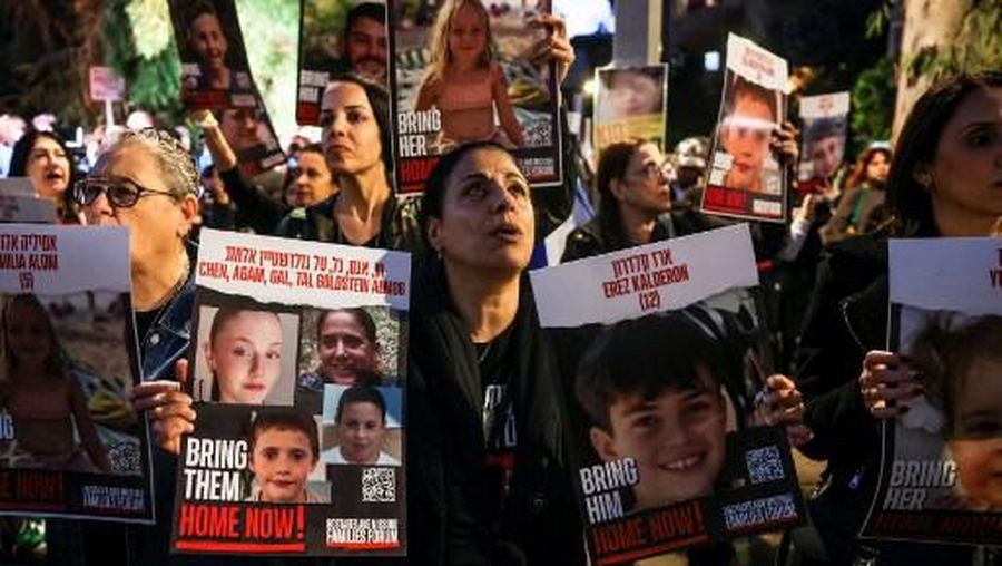 A woman holds portraits of hostages Erez Kalderon, 12, and of children of the Goldstein Almog family as protesters rally outside the Unicef offices in Tel Aviv on November 20, 2023 to demand the release of Israelis held hostage in Gaza since the October 7 attack by Hamas militants, amid ongoing battles between Israel and the Palestinian armed group. (Photo by AHMAD GHARABLI / AFP)