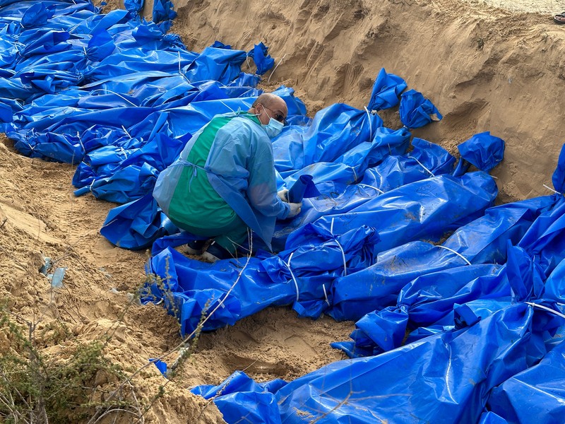 The bodies of Palestinians killed in Israeli strikes and fire are buried in a mass grave, after they were transported from Al Shifa hospital in Gaza City for burial, in Khan Younis in the southern Gaza Strip November 22, 2023. REUTERS/Mohammed Salem