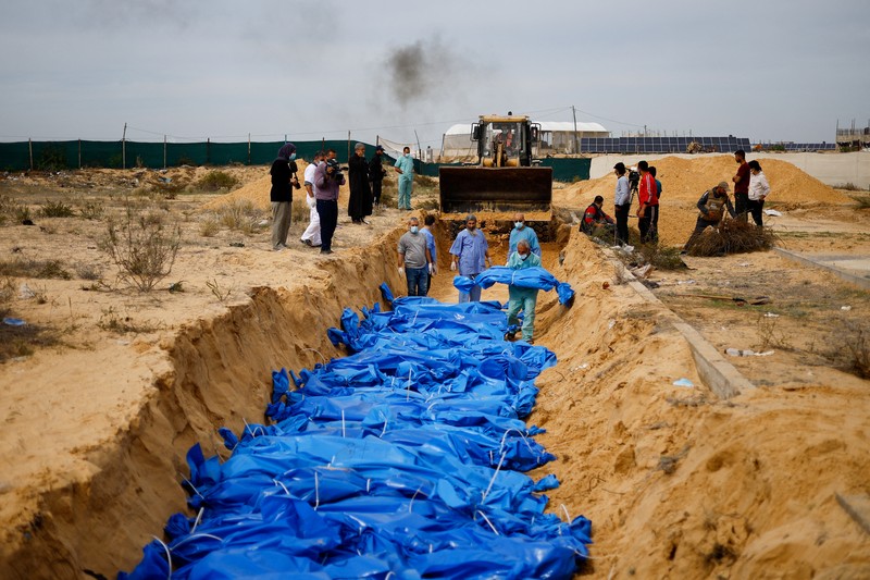 The bodies of Palestinians killed in Israeli strikes and fire are buried in a mass grave, after they were transported from Al Shifa hospital in Gaza City for burial, in Khan Younis in the southern Gaza Strip November 22, 2023. REUTERS/Mohammed Salem