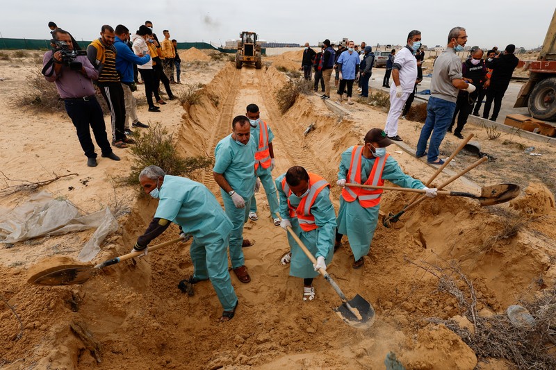 The bodies of Palestinians killed in Israeli strikes and fire are buried in a mass grave, after they were transported from Al Shifa hospital in Gaza City for burial, in Khan Younis in the southern Gaza Strip November 22, 2023. REUTERS/Mohammed Salem