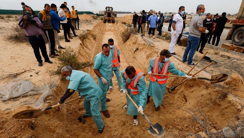 The bodies of Palestinians killed in Israeli strikes and fire are buried in a mass grave, after they were transported from Al Shifa hospital in Gaza City for burial, in Khan Younis in the southern Gaza Strip November 22, 2023. REUTERS/Mohammed Salem