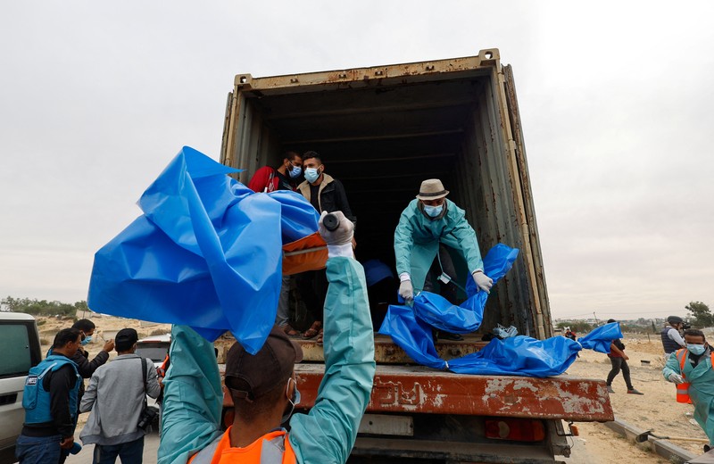 The bodies of Palestinians killed in Israeli strikes and fire are buried in a mass grave, after they were transported from Al Shifa hospital in Gaza City for burial, in Khan Younis in the southern Gaza Strip November 22, 2023. REUTERS/Mohammed Salem
