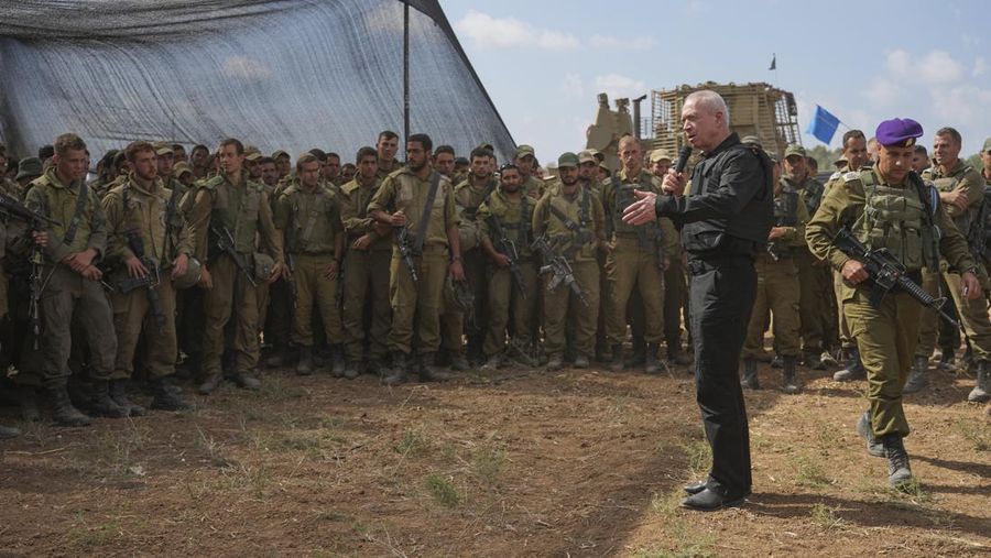 Israel's Defense Minister Yoav Gallant, wearing a protective vest, speaks with Israeli soldiers in a staging area near the border with the Gaza Strip in southern Israel, Thursday, Oct. 19, 2023. (AP Photo/Tsafrir Abayov)