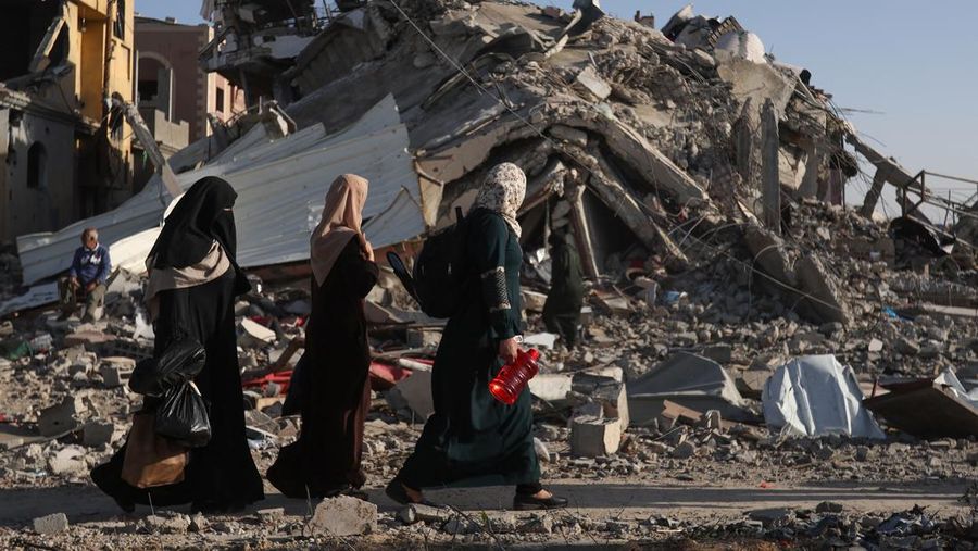 Pengungsi Palestina kembali ke rumah mereka saat mereka berjalan di dekat rumah-rumah yang hancur akibat serangan Israel selama konflik, di tengah gencatan senjata sementara antara Hamas dan Israel, di Khan Younis di selatan Jalur Gaza 24 November 2023. (REUTERS/Ibraheem Abu Mustafa)