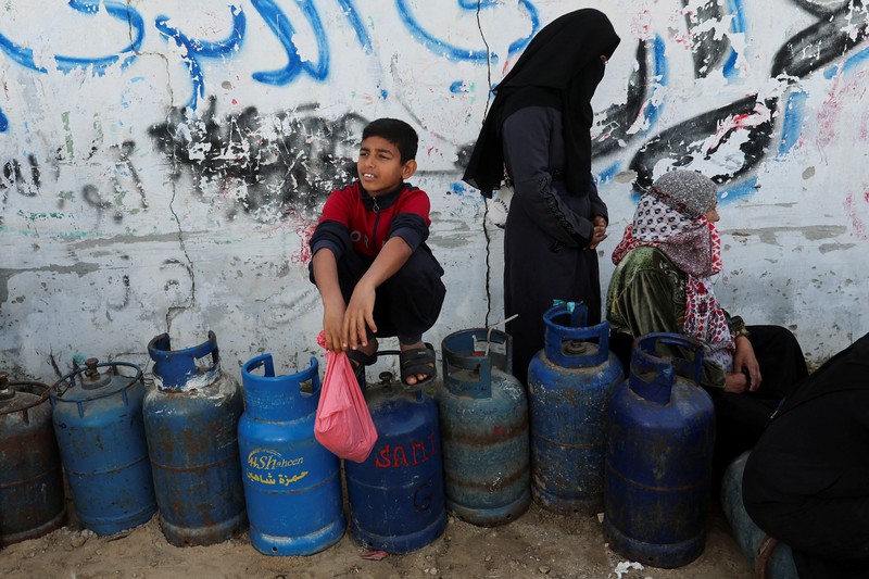 Truk bantuan bergerak di jalan ketika warga Palestina menyaksikan, selama gencatan senjata sementara antara Hamas dan Israel, di Rafah, di selatan Jalur Gaza 25 November 2023. Truk bantuan bergerak di jalan ketika warga Palestina menyaksikan, selama gencatan senjata sementara antara Hamas dan Israel, di Rafah, di selatan Jalur Gaza 25 November 2023. (REUTERS/Ibraheem Abu Mustafa)