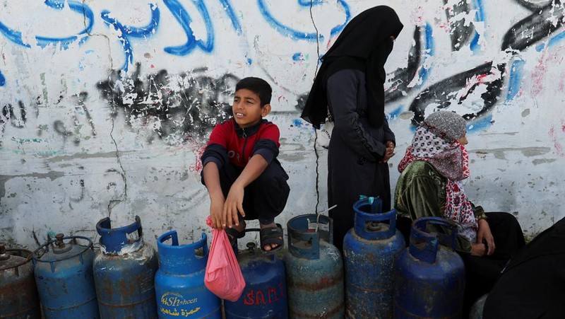 Truk bantuan bergerak di jalan ketika warga Palestina menyaksikan, selama gencatan senjata sementara antara Hamas dan Israel, di Rafah, di selatan Jalur Gaza 25 November 2023. (REUTERS/Ibraheem Abu Mustafa)
