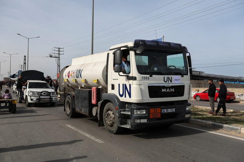 Truk bantuan bergerak di jalan ketika warga Palestina menyaksikan, selama gencatan senjata sementara antara Hamas dan Israel, di Rafah, di selatan Jalur Gaza 25 November 2023. Truk bantuan bergerak di jalan ketika warga Palestina menyaksikan, selama gencatan senjata sementara antara Hamas dan Israel, di Rafah, di selatan Jalur Gaza 25 November 2023. (REUTERS/Ibraheem Abu Mustafa)