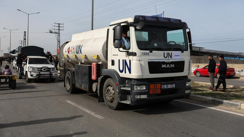 Truk bantuan bergerak di jalan ketika warga Palestina menyaksikan, selama gencatan senjata sementara antara Hamas dan Israel, di Rafah, di selatan Jalur Gaza 25 November 2023. (REUTERS/Ibraheem Abu Mustafa)
