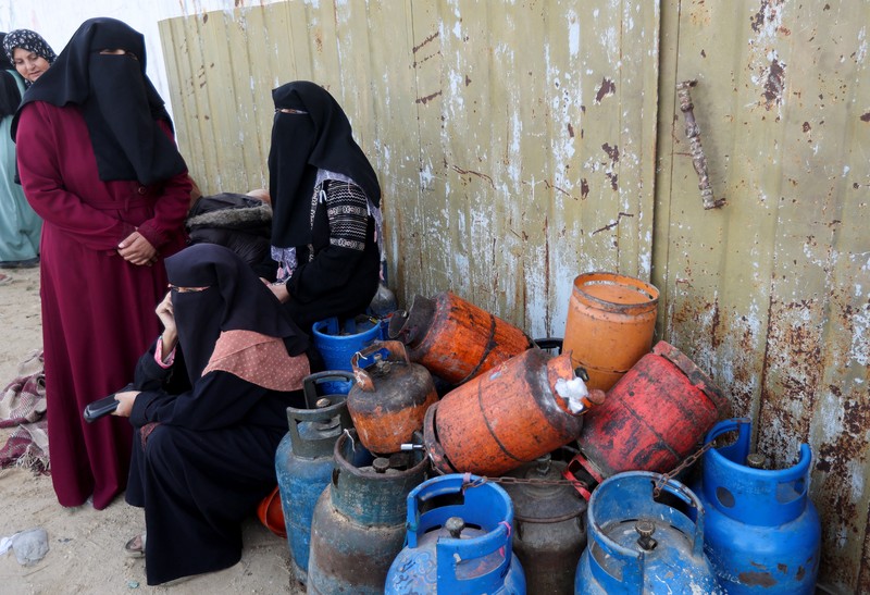 Truk bantuan bergerak di jalan ketika warga Palestina menyaksikan, selama gencatan senjata sementara antara Hamas dan Israel, di Rafah, di selatan Jalur Gaza 25 November 2023. (REUTERS/Ibraheem Abu Mustafa)