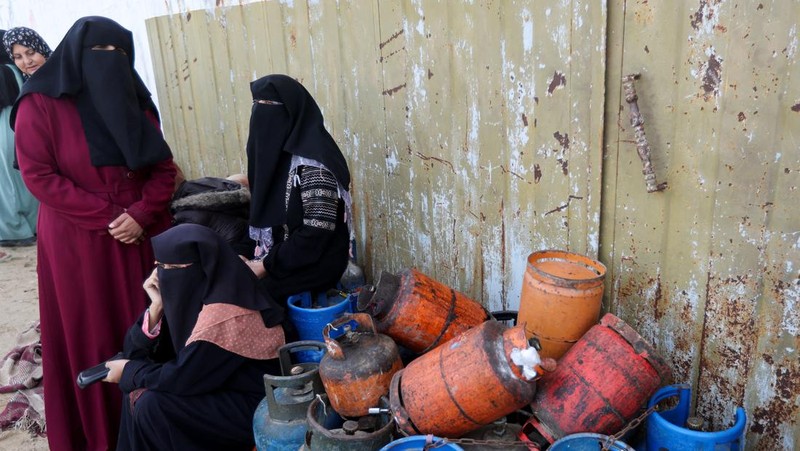 Truk bantuan bergerak di jalan ketika warga Palestina menyaksikan, selama gencatan senjata sementara antara Hamas dan Israel, di Rafah, di selatan Jalur Gaza 25 November 2023. (REUTERS/Ibraheem Abu Mustafa)