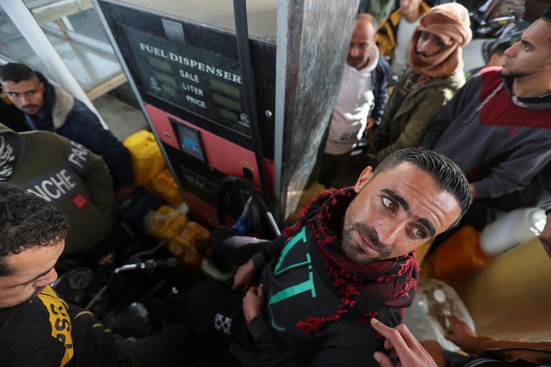 Truk bantuan bergerak di jalan ketika warga Palestina menyaksikan, selama gencatan senjata sementara antara Hamas dan Israel, di Rafah, di selatan Jalur Gaza 25 November 2023. (REUTERS/Ibraheem Abu Mustafa)
