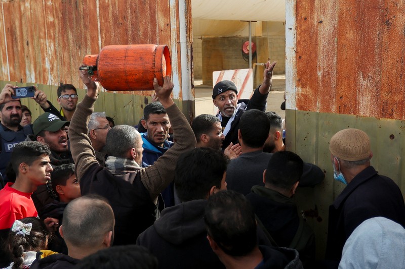 Truk bantuan bergerak di jalan ketika warga Palestina menyaksikan, selama gencatan senjata sementara antara Hamas dan Israel, di Rafah, di selatan Jalur Gaza 25 November 2023. (REUTERS/Ibraheem Abu Mustafa)