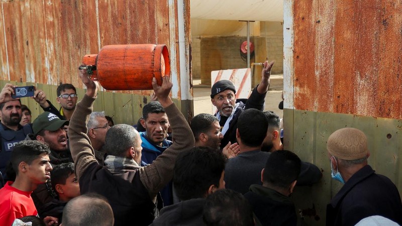 Truk bantuan bergerak di jalan ketika warga Palestina menyaksikan, selama gencatan senjata sementara antara Hamas dan Israel, di Rafah, di selatan Jalur Gaza 25 November 2023. (REUTERS/Ibraheem Abu Mustafa)
