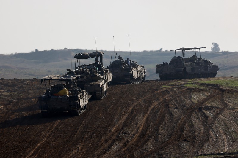 ISRAEL-PALESTINIANS/TRUCE Israeli soldiers hold an Israeli flag atop of a military vehicle, near Israel's border after leaving Gaza, during the temporary truce between the Palestinian Islamist group Hamas and Israel, in Israel, November 24, 2023. REUTERS/Amir Cohen