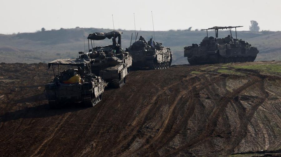 Israeli soldiers hold an Israeli flag atop of a military vehicle, near Israel's border after leaving Gaza, during the temporary truce between the Palestinian Islamist group Hamas and Israel, in Israel, November 24, 2023. REUTERS/Amir Cohen