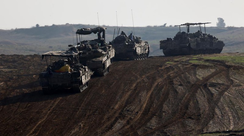 Israeli soldiers hold an Israeli flag atop of a military vehicle, near Israel's border after leaving Gaza, during the temporary truce between the Palestinian Islamist group Hamas and Israel, in Israel, November 24, 2023. REUTERS/Amir Cohen
