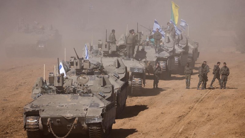Israeli soldiers hold an Israeli flag atop of a military vehicle, near Israel's border after leaving Gaza, during the temporary truce between the Palestinian Islamist group Hamas and Israel, in Israel, November 24, 2023. REUTERS/Amir Cohen