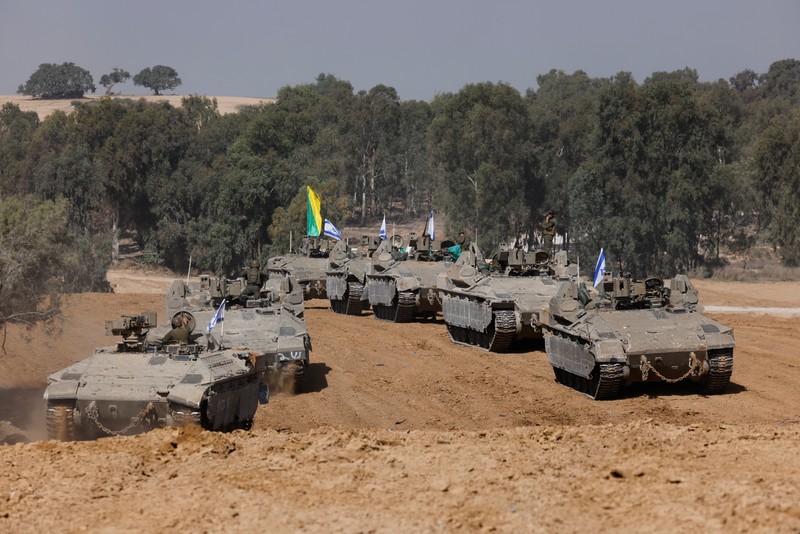 ISRAEL-PALESTINIANS/TRUCE Israeli soldiers hold an Israeli flag atop of a military vehicle, near Israel's border after leaving Gaza, during the temporary truce between the Palestinian Islamist group Hamas and Israel, in Israel, November 24, 2023. REUTERS/Amir Cohen