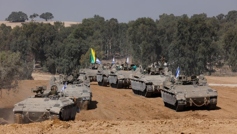 Israeli soldiers hold an Israeli flag atop of a military vehicle, near Israel's border after leaving Gaza, during the temporary truce between the Palestinian Islamist group Hamas and Israel, in Israel, November 24, 2023. REUTERS/Amir Cohen