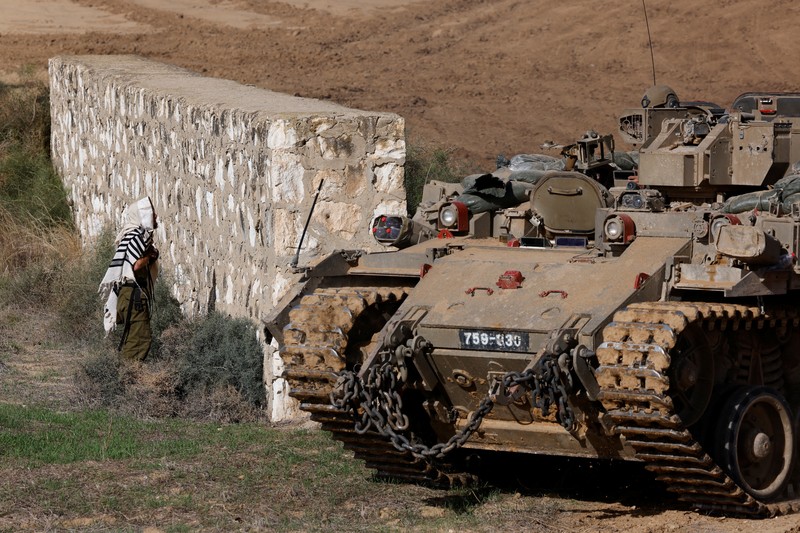 ISRAEL-PALESTINIANS/TRUCE Israeli soldiers hold an Israeli flag atop of a military vehicle, near Israel's border after leaving Gaza, during the temporary truce between the Palestinian Islamist group Hamas and Israel, in Israel, November 24, 2023. REUTERS/Amir Cohen