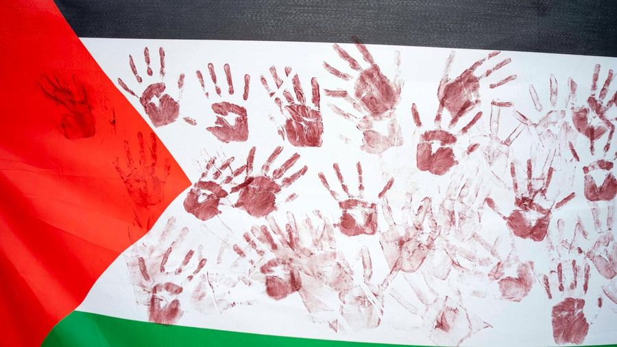 Bendera Palestina dengan cetakan tangan merah dibawa saat demonstrasi pro-Palestina di luar Gedung Putih di Washington, AS, 2 Desember 2023. Orang-orang berkumpul dalam solidaritas setelah gencatan senjata sementara berakhir antara Israel dan Hamas awal pekan ini. (REUTERS/Bonnie Cash)