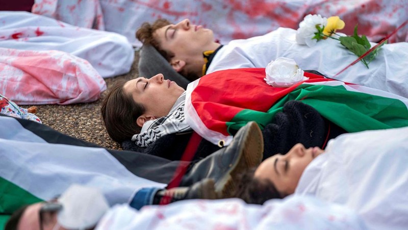 Demonstran pro-Palestina yang mengenakan kain putih tergeletak di tanah di luar Gedung Putih di Washington, AS, 2 Desember 2023. Orang-orang berkumpul dalam solidaritas setelah gencatan senjata sementara antara Israel dan Hamas berakhir awal pekan ini. (REUTERS/Bonnie Cash)