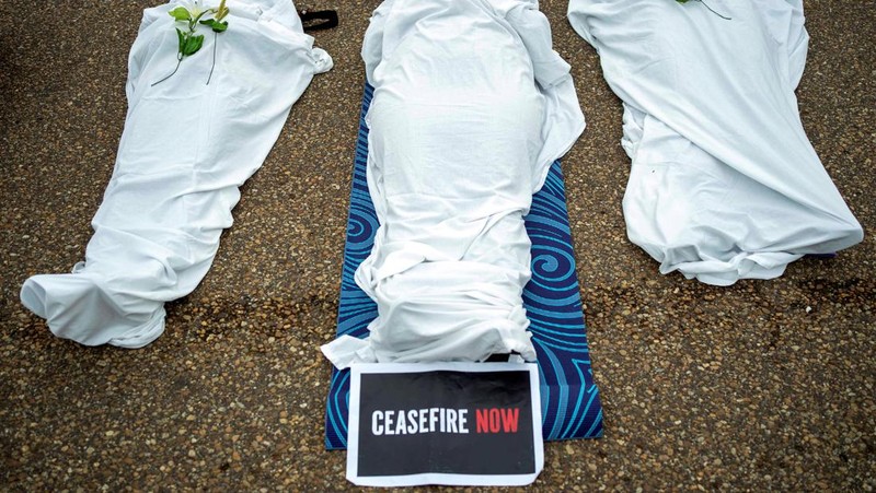 Demonstran pro-Palestina yang mengenakan kain putih tergeletak di tanah di luar Gedung Putih di Washington, AS, 2 Desember 2023. Orang-orang berkumpul dalam solidaritas setelah gencatan senjata sementara antara Israel dan Hamas berakhir awal pekan ini. (REUTERS/Bonnie Cash)