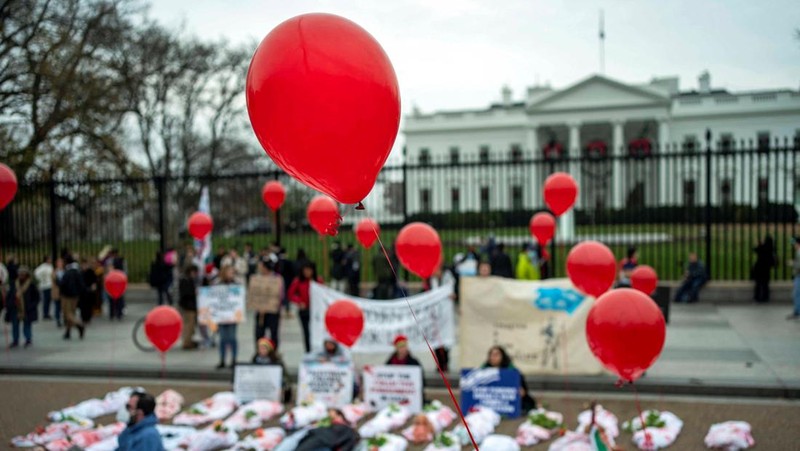 Demonstran pro-Palestina yang mengenakan kain putih tergeletak di tanah di luar Gedung Putih di Washington, AS, 2 Desember 2023. Orang-orang berkumpul dalam solidaritas setelah gencatan senjata sementara antara Israel dan Hamas berakhir awal pekan ini. (REUTERS/Bonnie Cash)