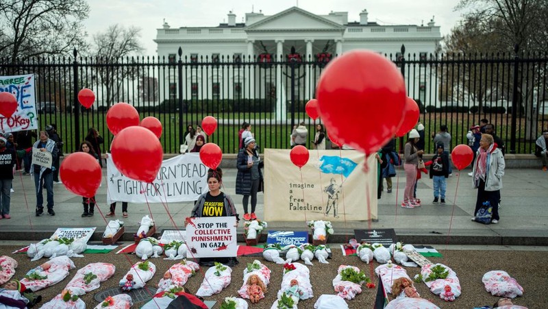 Demonstran pro-Palestina yang mengenakan kain putih tergeletak di tanah di luar Gedung Putih di Washington, AS, 2 Desember 2023. Orang-orang berkumpul dalam solidaritas setelah gencatan senjata sementara antara Israel dan Hamas berakhir awal pekan ini. (REUTERS/Bonnie Cash)